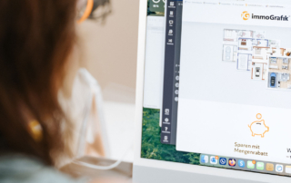 Frau sitzt vor einem Computerbildschirm und sieht sich die Website von ImmoGrafik an.